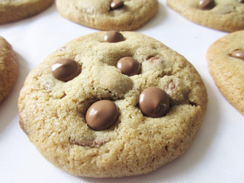 6 chocolate chip cookies arranged on white surface.
