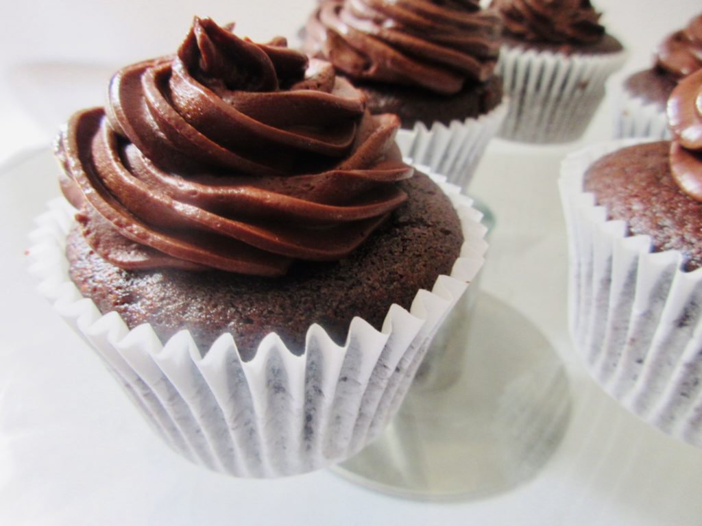 Double chocolate cupcakes with whipped ganache frosting from a side view.