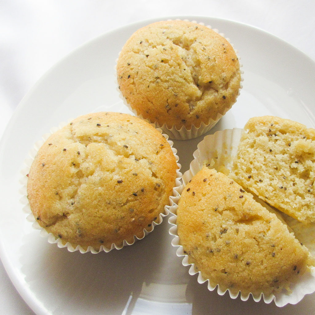 3 lemon chia muffins on a plate with 1 cut in half.