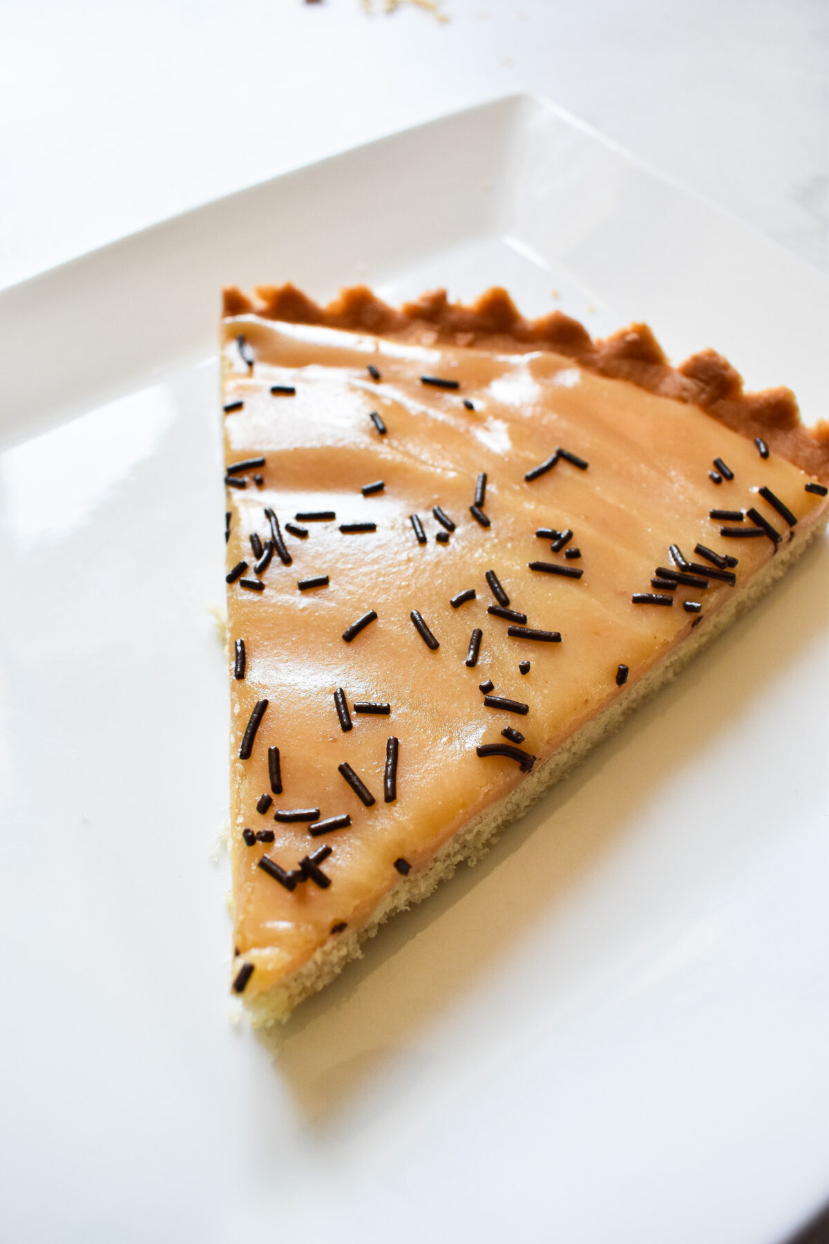 A slice of caramel tart on a white plate.