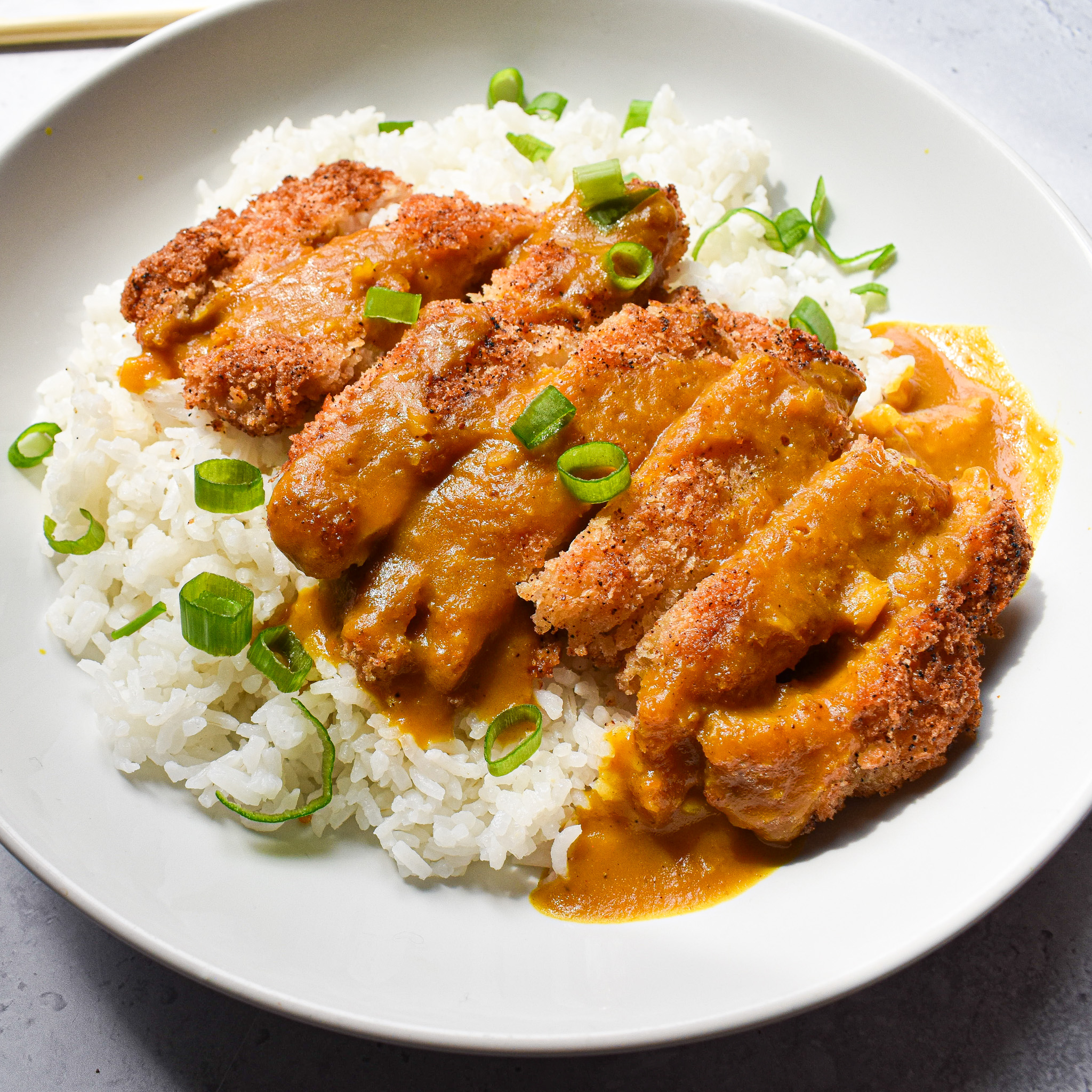 Crispy chicken and rice in white bowl.