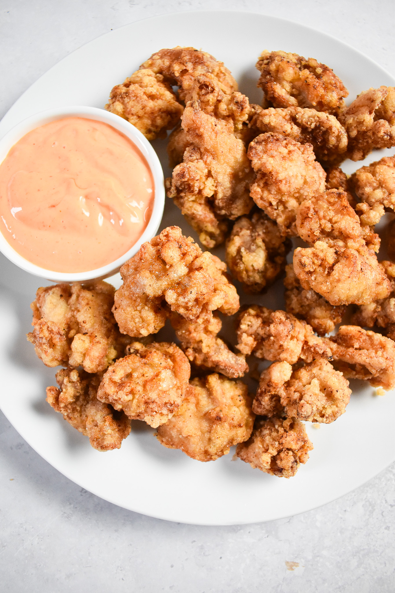 Japanese fried thighs on a plate next to a pot of sauce.