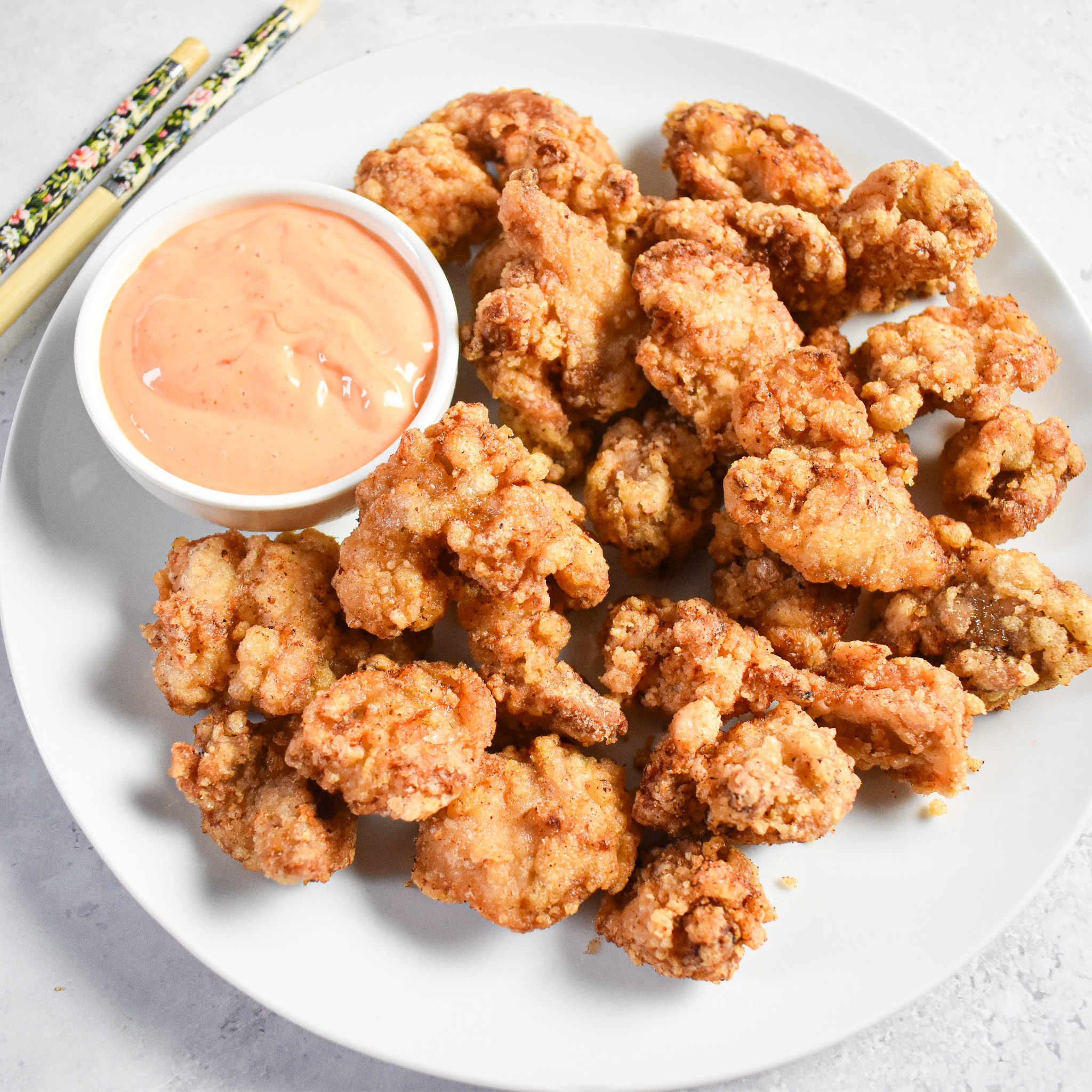 chicken karaage with pot of sauce and chopsticks in the background.