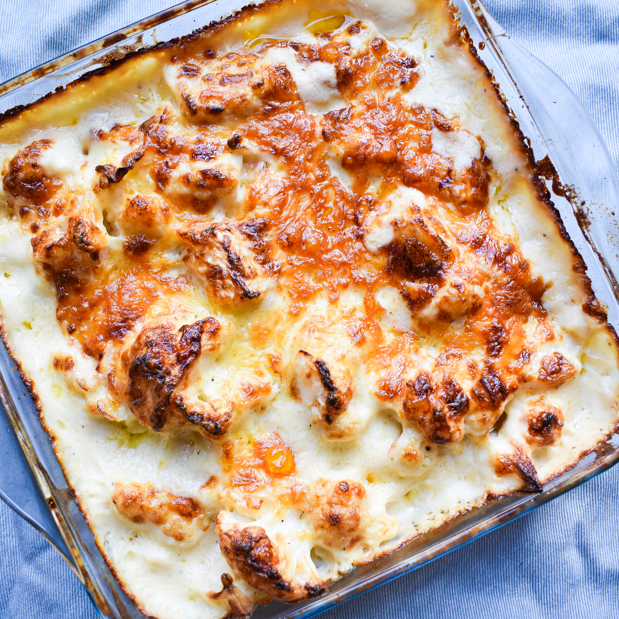 Creamy cauliflower cheese in clear dish.
