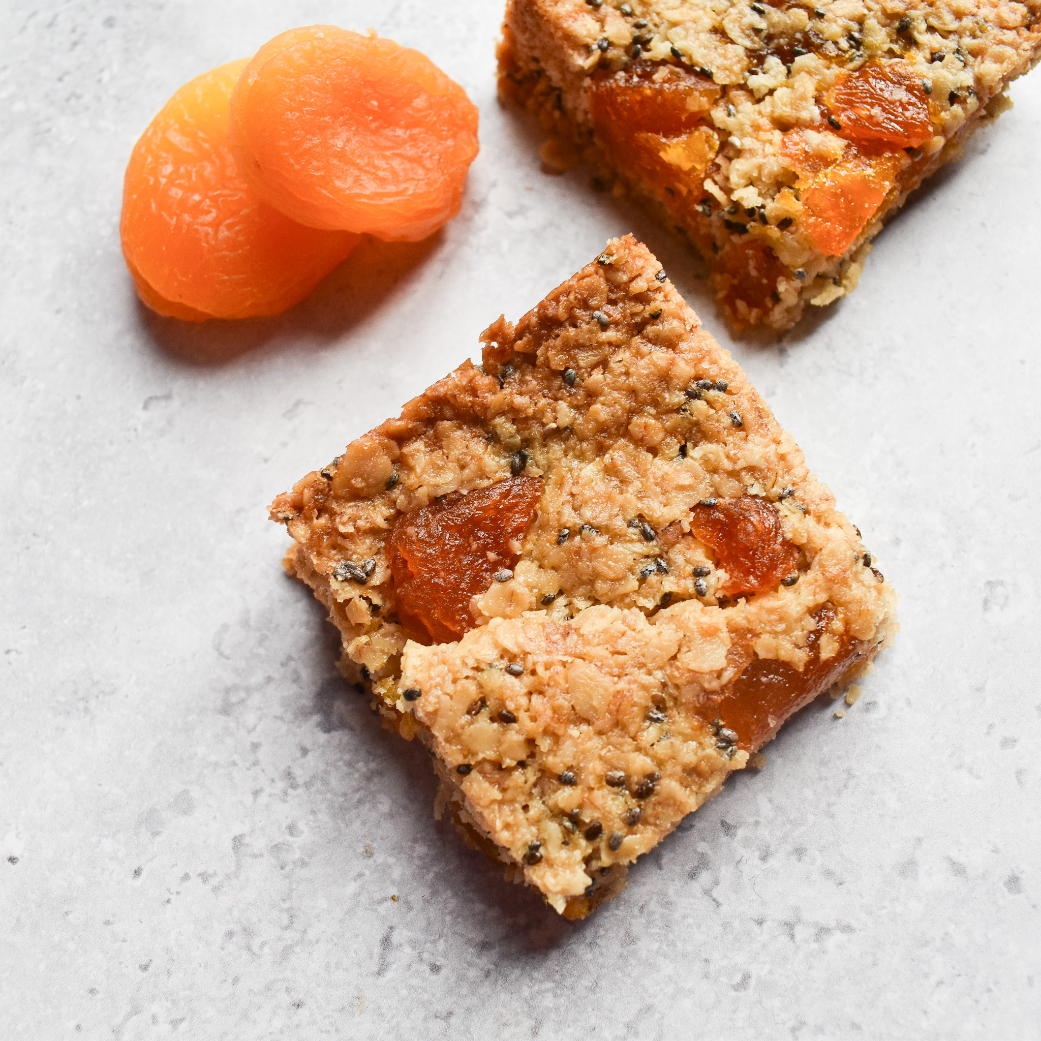 Apricot flapjacks next to 2 dried apricots.