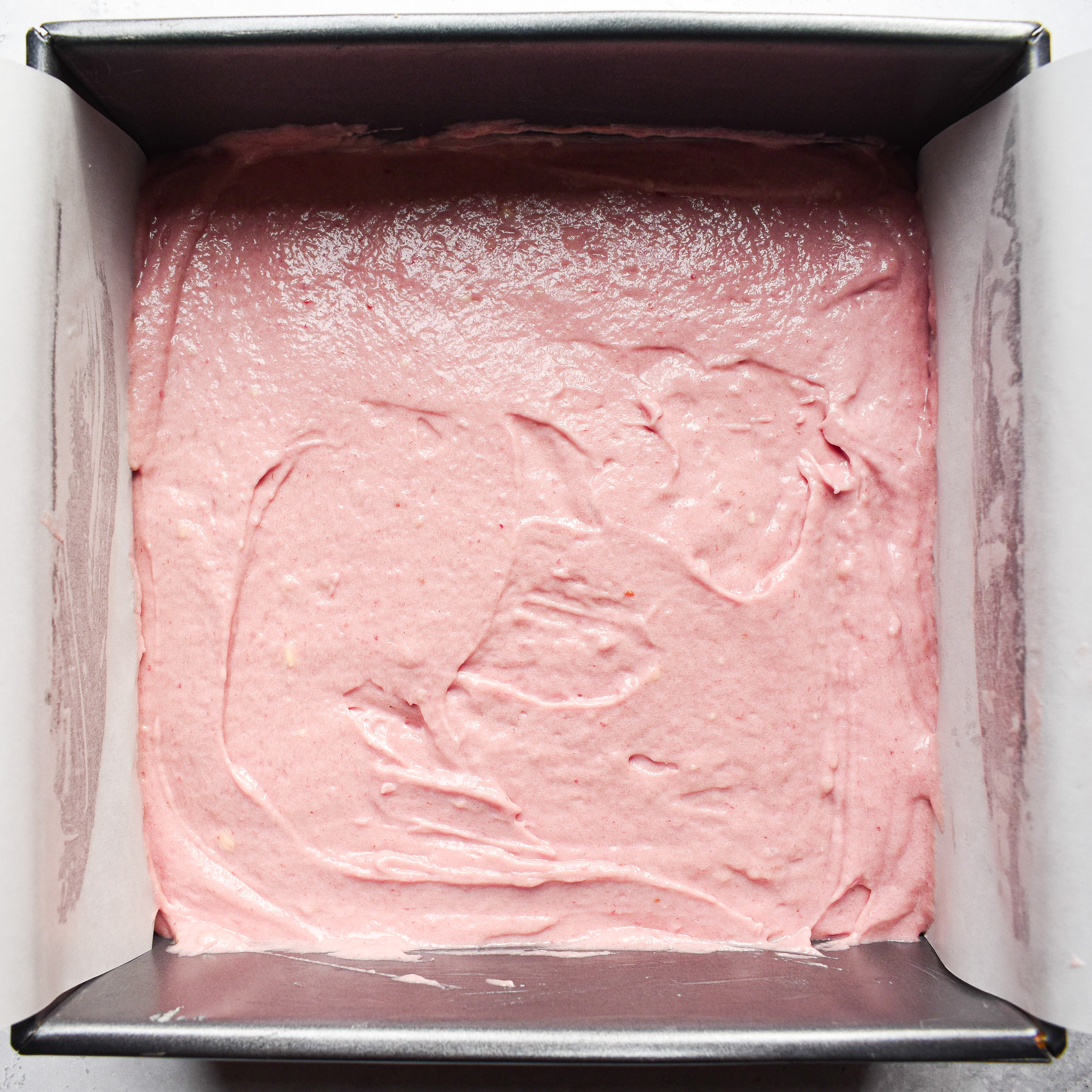 pink batter in a square baking tin.