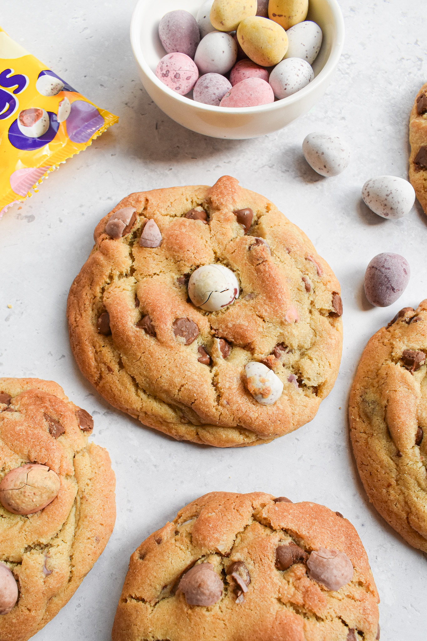 Chocolate chip cookies with a bowl of mini eggs above it.