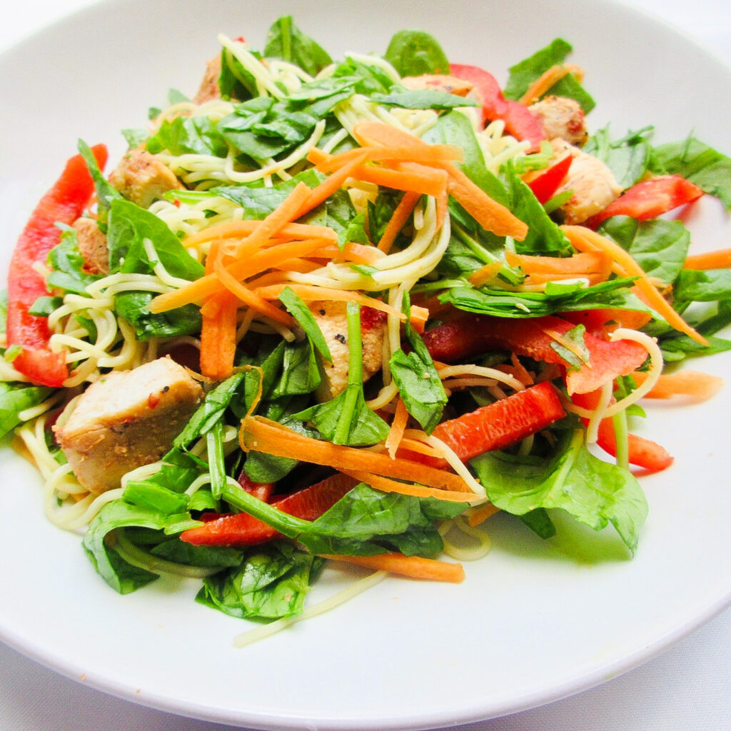Chicken noodle salad on a white plate.
